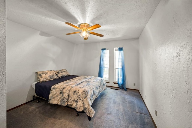 bedroom with dark colored carpet, ceiling fan, and a textured ceiling