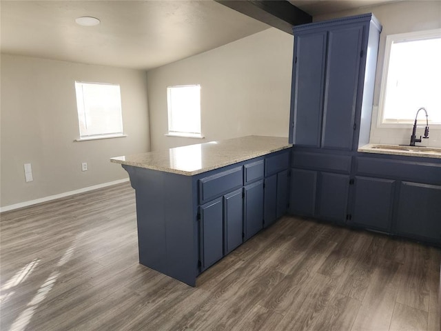 kitchen featuring kitchen peninsula, dark hardwood / wood-style flooring, sink, and blue cabinetry