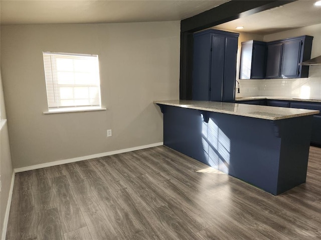 kitchen with black cooktop, decorative backsplash, a kitchen breakfast bar, dark hardwood / wood-style floors, and kitchen peninsula