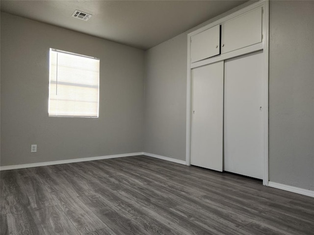 unfurnished bedroom with a closet and dark hardwood / wood-style floors