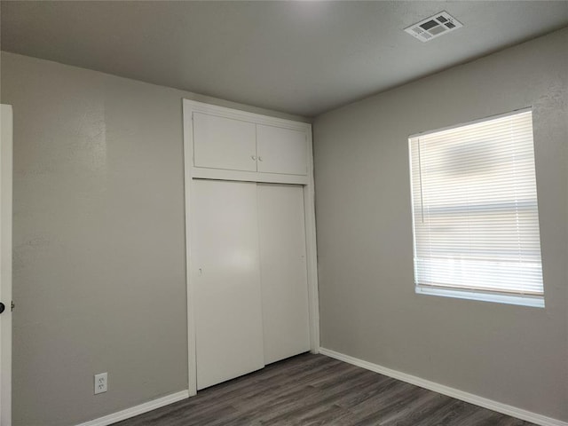 unfurnished bedroom featuring dark wood-type flooring and a closet