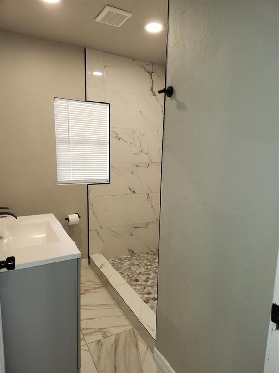 bathroom with vanity and tiled shower