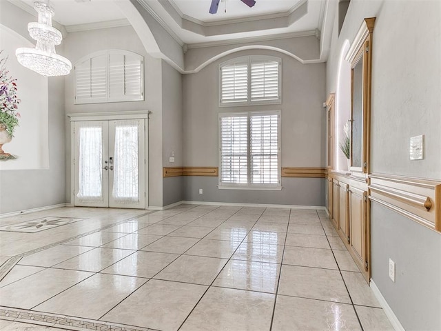 foyer with a towering ceiling, french doors, ceiling fan with notable chandelier, and ornamental molding