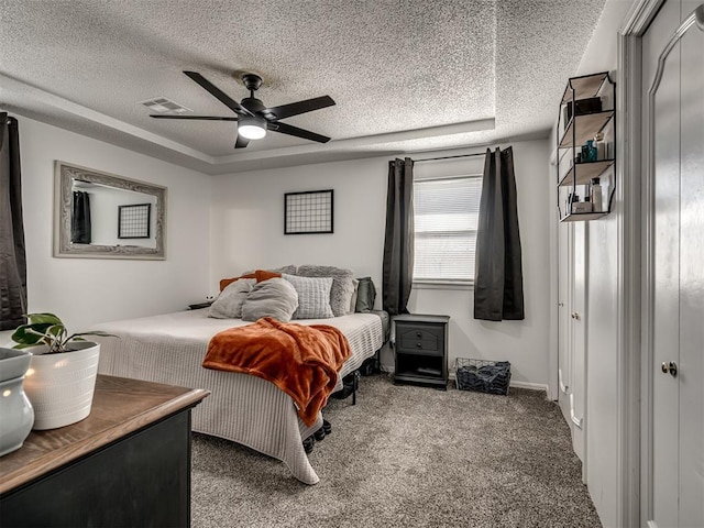 carpeted bedroom with ceiling fan, a tray ceiling, and a textured ceiling