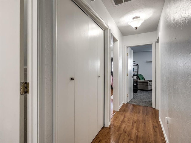 hallway with hardwood / wood-style floors and a textured ceiling