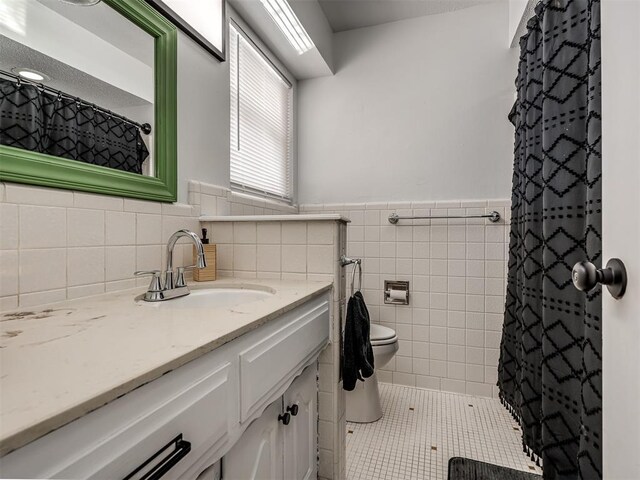 bathroom with vanity, tile walls, tile patterned floors, and toilet