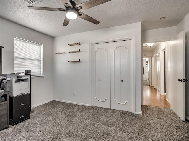 bedroom featuring ceiling fan, carpet flooring, a closet, and a textured ceiling