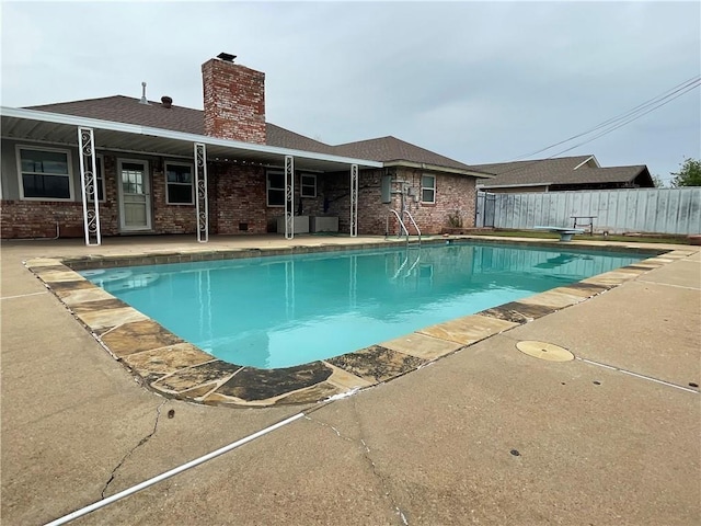 view of swimming pool with a patio area and a diving board