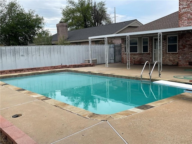 view of pool with a diving board and a patio area