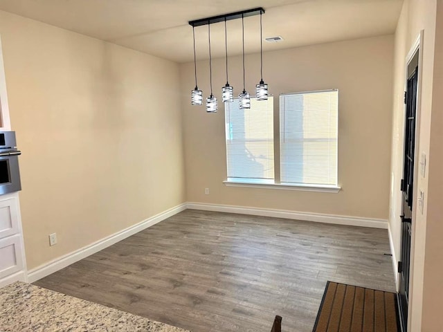 unfurnished dining area featuring dark wood-style floors, visible vents, and baseboards