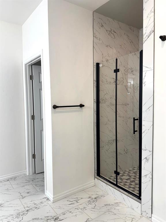 bathroom with marble finish floor, a marble finish shower, and baseboards