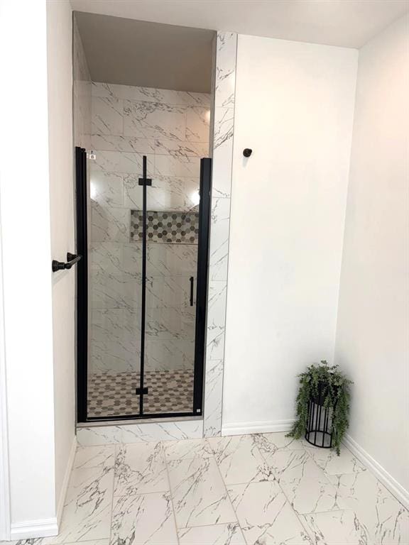 bathroom with marble finish floor, a marble finish shower, and baseboards