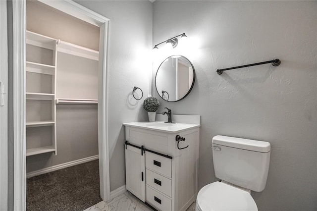 bathroom featuring toilet, marble finish floor, vanity, and baseboards