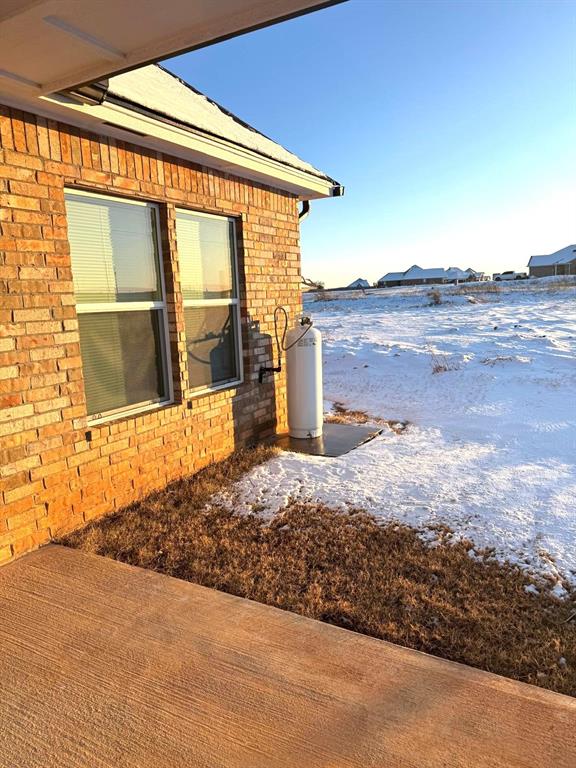 snow covered property with brick siding