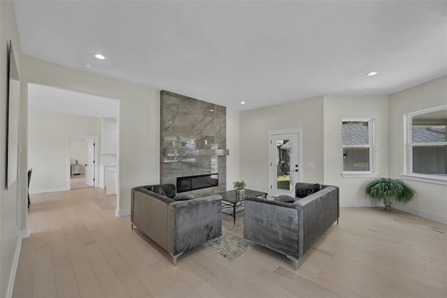 living room with a high end fireplace and light wood-type flooring