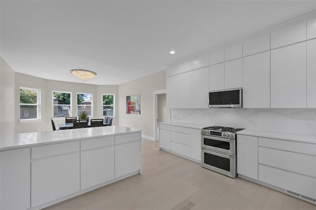 kitchen featuring white cabinets, stainless steel appliances, tasteful backsplash, and a notable chandelier