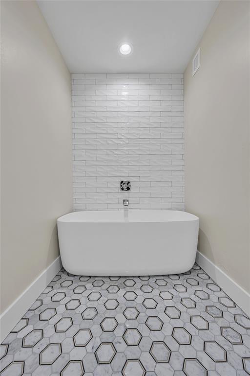 bathroom with a tub to relax in and tile patterned flooring