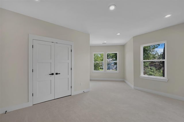 unfurnished bedroom featuring light colored carpet and a closet