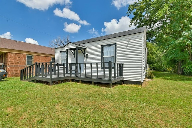 back of property featuring a wooden deck and a lawn