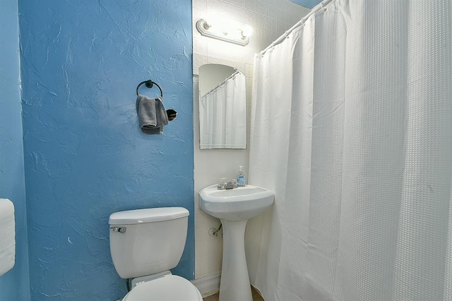 bathroom featuring a shower with curtain and toilet