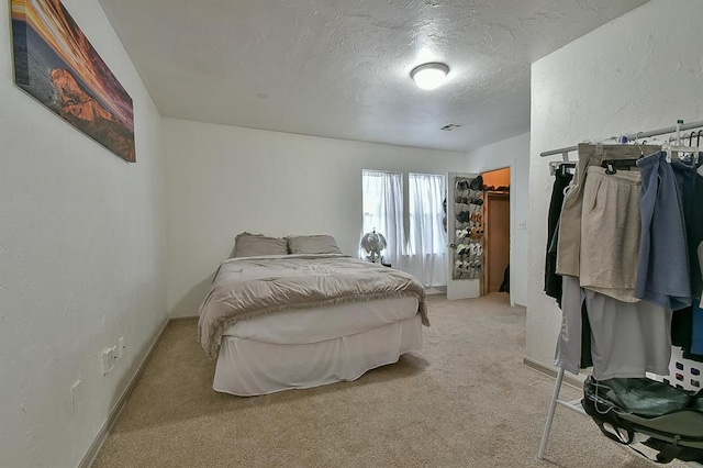 carpeted bedroom with a walk in closet and a textured ceiling