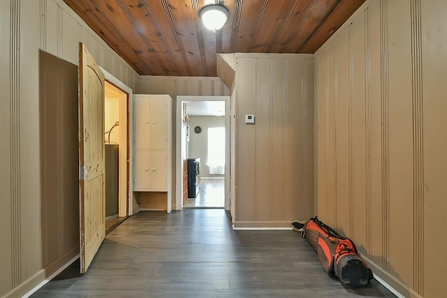 corridor featuring dark wood-type flooring, wooden ceiling, and wooden walls