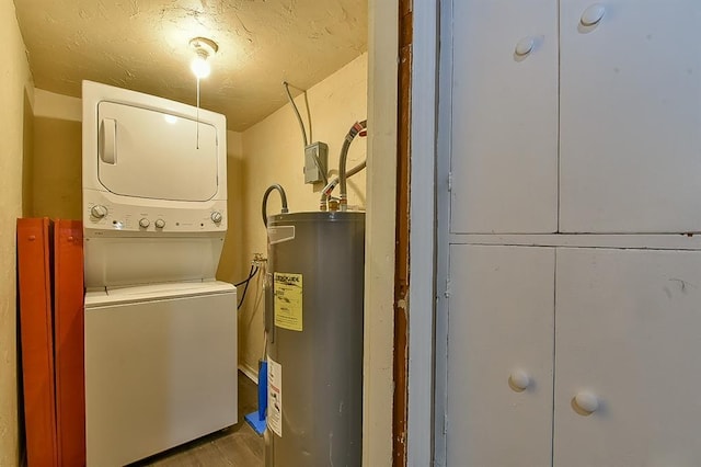 laundry area featuring stacked washer / drying machine, electric water heater, and a textured ceiling