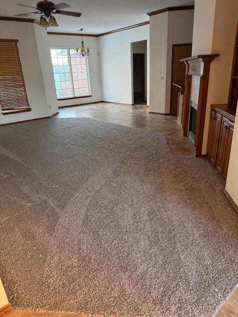 unfurnished living room with crown molding, carpet floors, and ceiling fan with notable chandelier