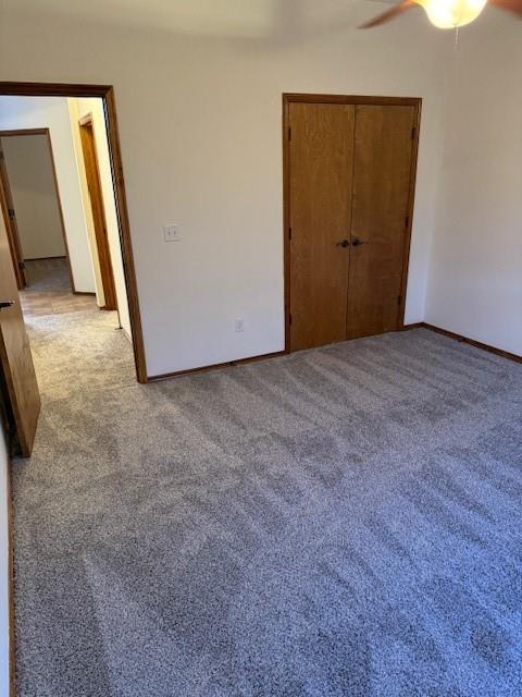 unfurnished bedroom featuring ceiling fan, a closet, and light carpet