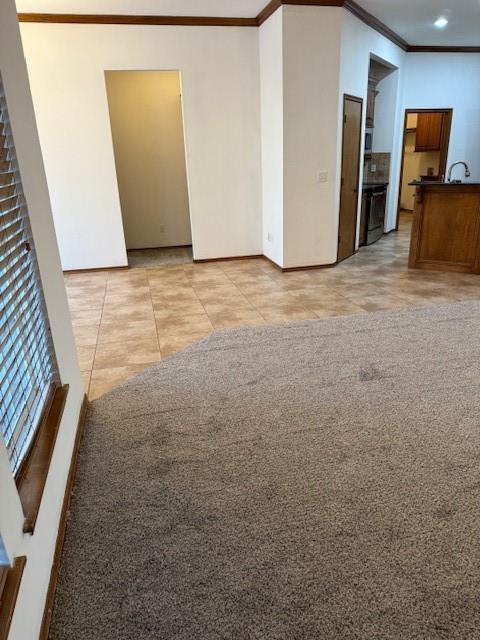 unfurnished living room with light tile patterned floors, ornamental molding, and sink