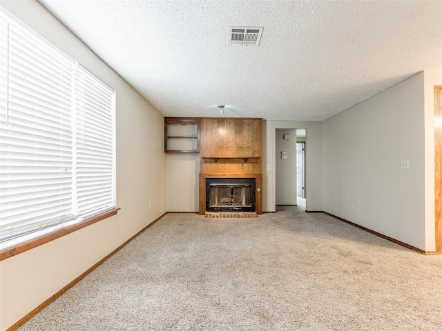 unfurnished living room with carpet, a textured ceiling, and a fireplace