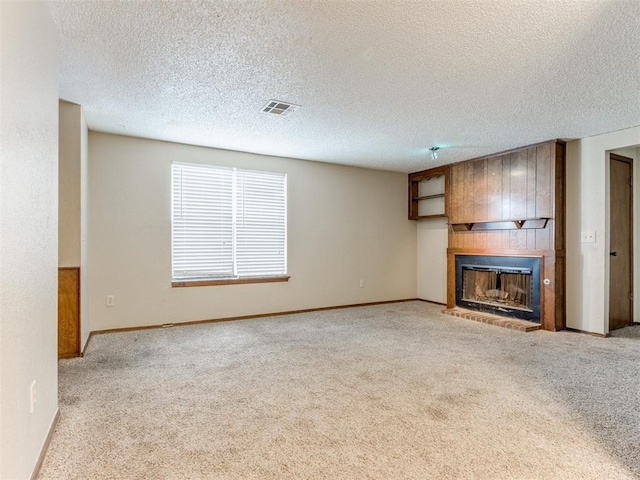 unfurnished living room with a textured ceiling, light colored carpet, and a large fireplace