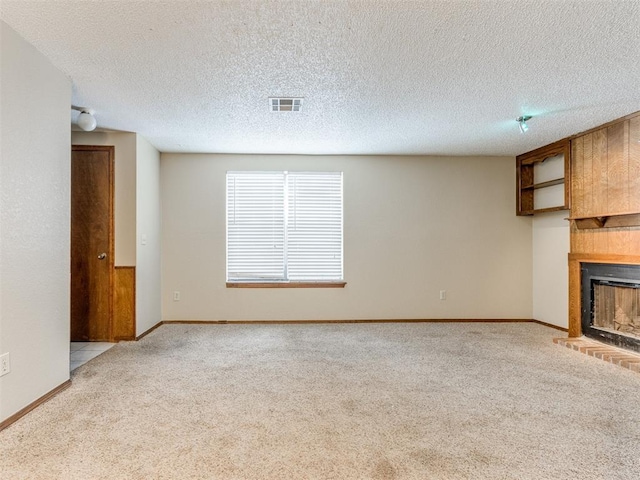 unfurnished living room featuring light colored carpet, a textured ceiling, and a fireplace