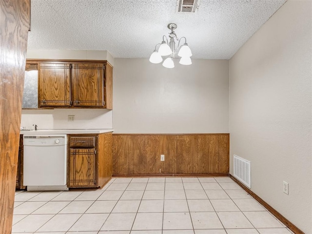 kitchen with dishwasher, wooden walls, pendant lighting, and a textured ceiling