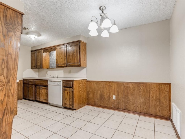 kitchen with white dishwasher, decorative light fixtures, a textured ceiling, a notable chandelier, and wood walls