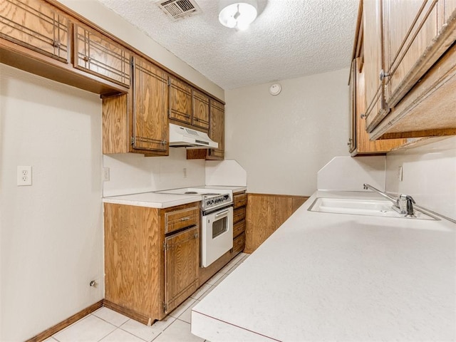 kitchen featuring sink, wood walls, electric range, and a textured ceiling