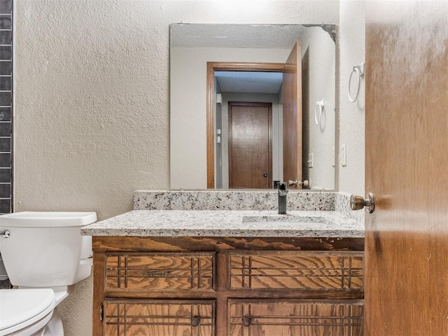 bathroom with vanity, toilet, and a textured ceiling