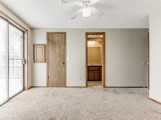 unfurnished bedroom featuring a textured ceiling, ensuite bath, access to outside, ceiling fan, and light colored carpet