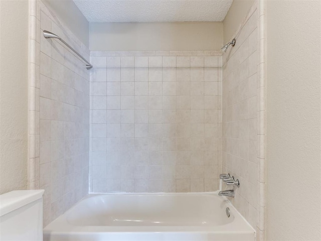 bathroom featuring tub / shower combination, a textured ceiling, and toilet