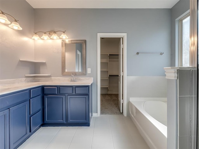 bathroom with tile patterned flooring, a washtub, and vanity