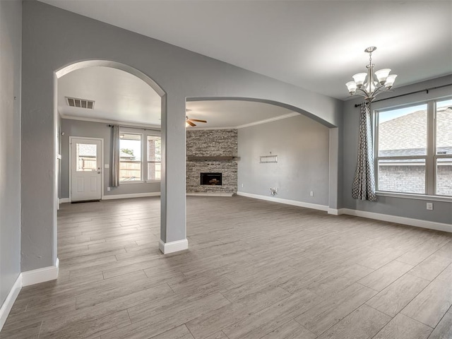 unfurnished living room with a fireplace, ceiling fan with notable chandelier, and ornamental molding