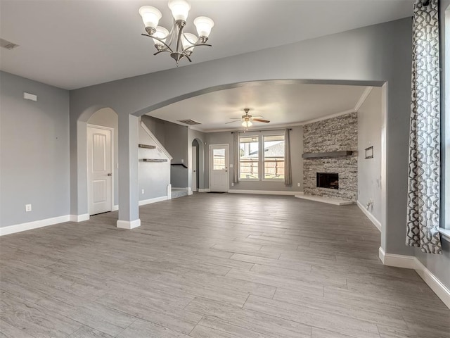 unfurnished living room with hardwood / wood-style flooring, ceiling fan with notable chandelier, ornamental molding, and a fireplace