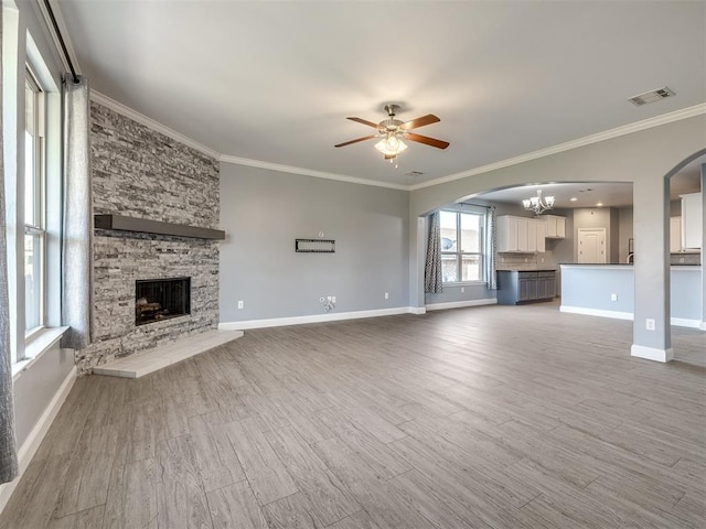 unfurnished living room with hardwood / wood-style floors, ceiling fan with notable chandelier, crown molding, and a fireplace