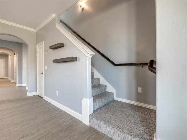 stairway with crown molding and hardwood / wood-style floors