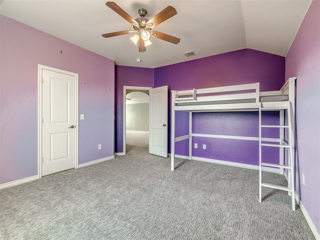 unfurnished bedroom featuring carpet floors, a closet, vaulted ceiling, and ceiling fan