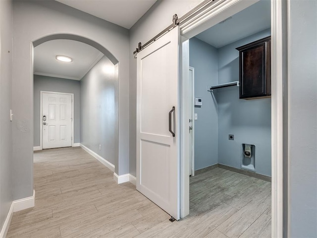 hall with a barn door, crown molding, and light hardwood / wood-style flooring