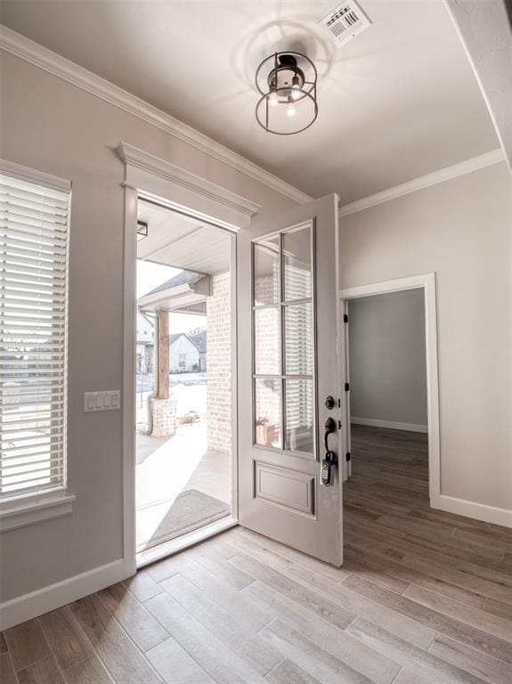 foyer entrance with crown molding, baseboards, visible vents, and light wood-type flooring