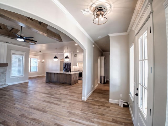 foyer entrance with visible vents, crown molding, light wood-type flooring, and baseboards