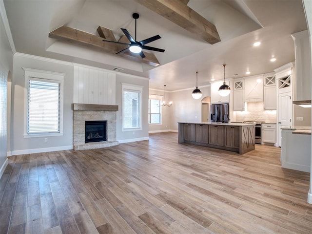 kitchen featuring light wood-style flooring, ceiling fan with notable chandelier, open floor plan, appliances with stainless steel finishes, and white cabinets