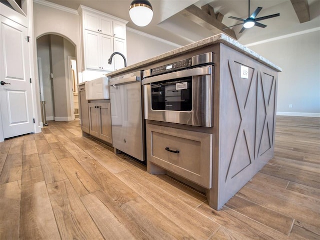 kitchen featuring stainless steel oven, light wood-style flooring, crown molding, and arched walkways